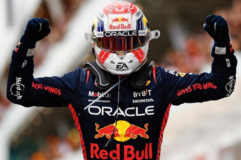 Max Verstappen in racing suit with hands up in the air in happiness
