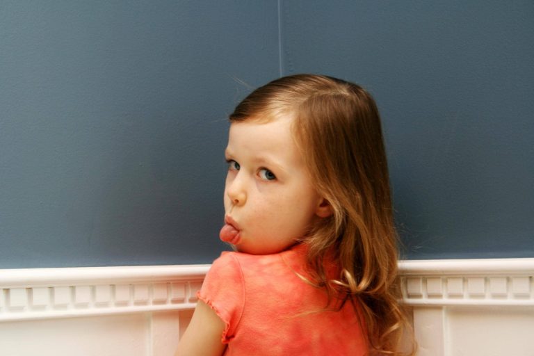 a child in time out looking back with her tongue poking out