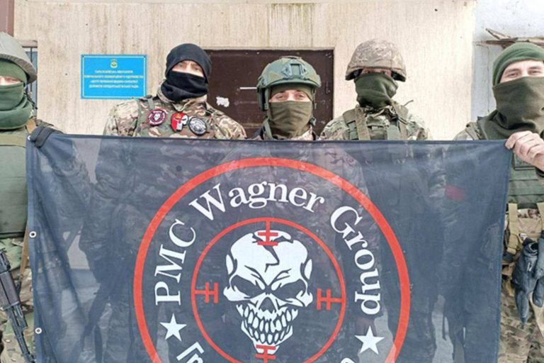 The Wagner Group dressed in military uniform and holding the fWagner Group flag