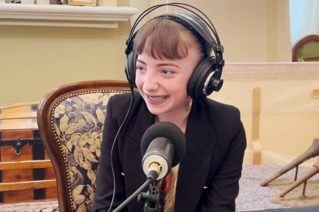 Isabella Taylor sitting att he dining room tabkle in front of a microphone