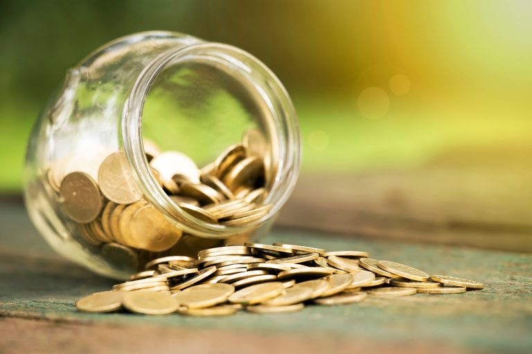 A jar of coins fallen over on the ground