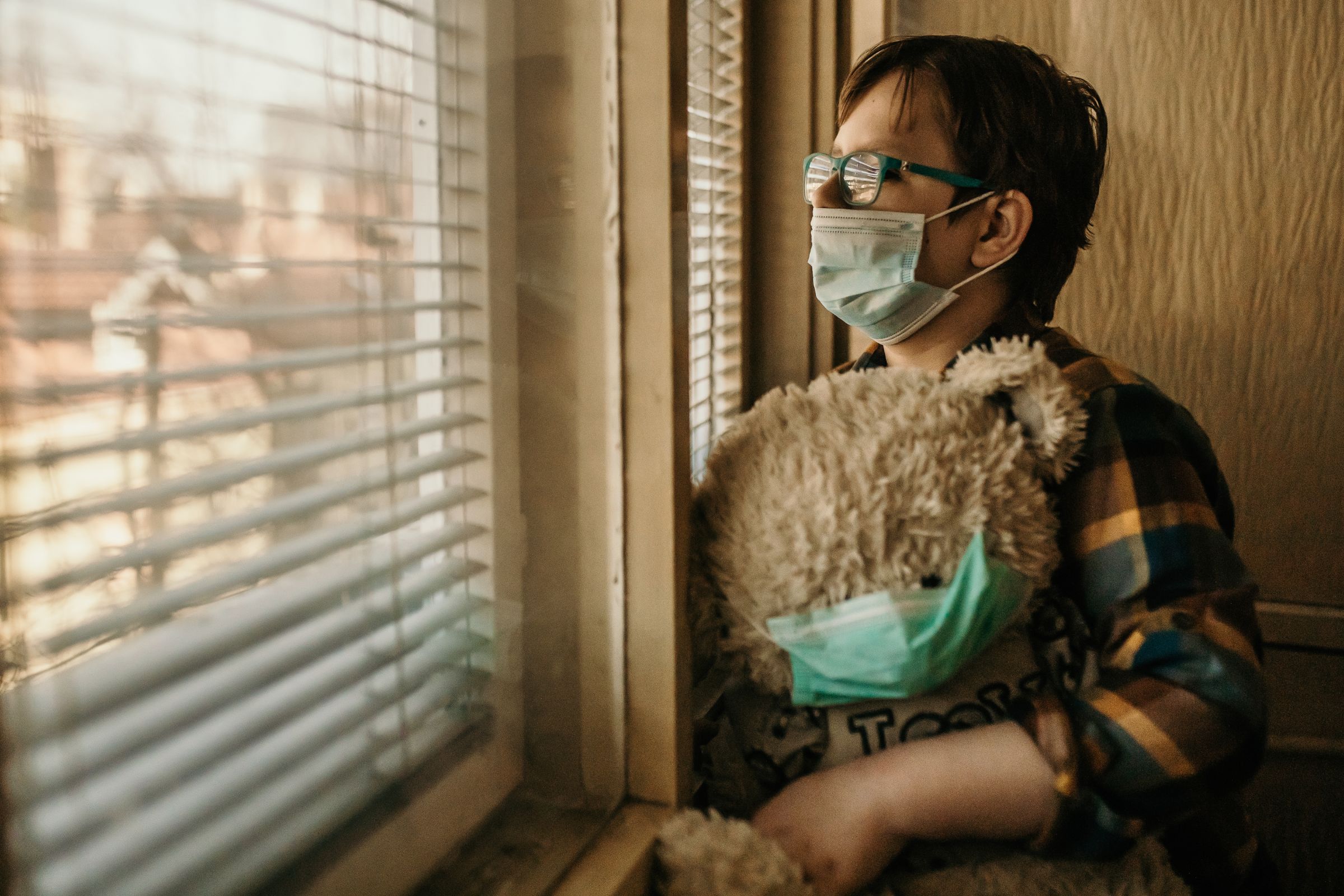 A Lady with a face mask holding a teddy bear with a face mask