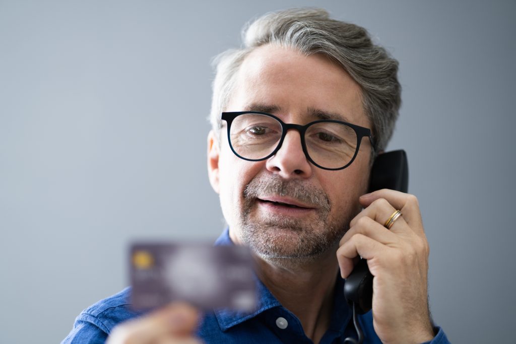 A man on the phone looking at his credit card