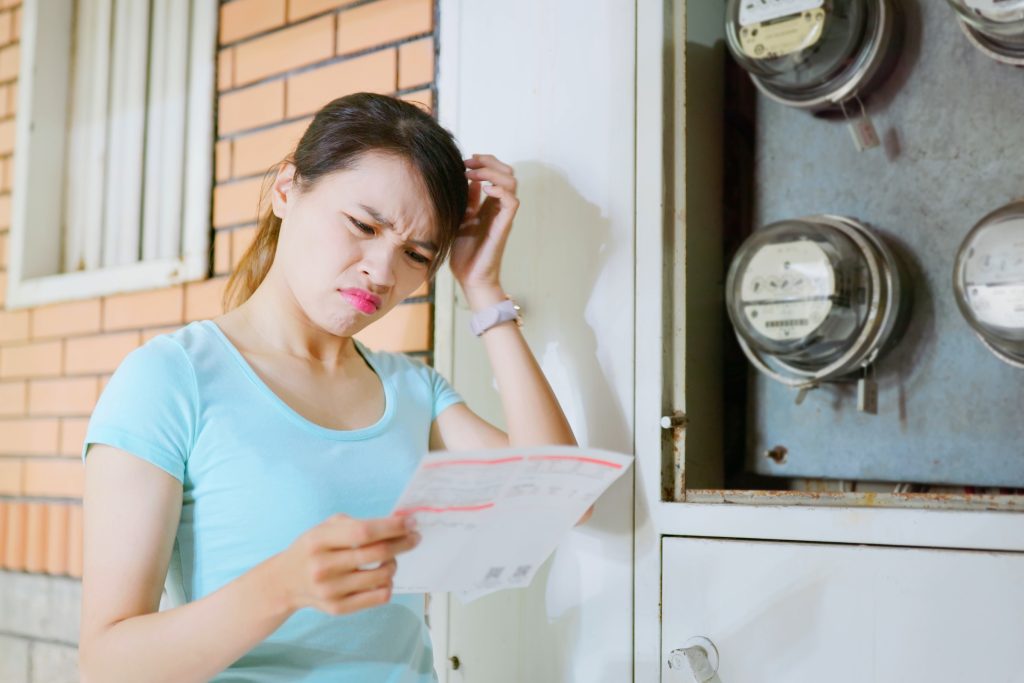 A young lady looking at her electricity bill confused why it's so expensive