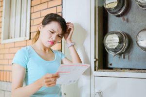 A young lady looking at her electricity bill confused why it's so expensive