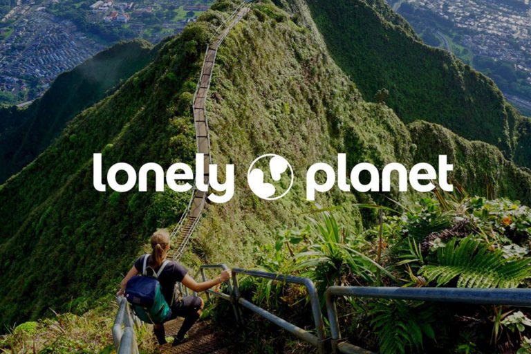 Lonely planet logo with the background of a walkway on a mountain top