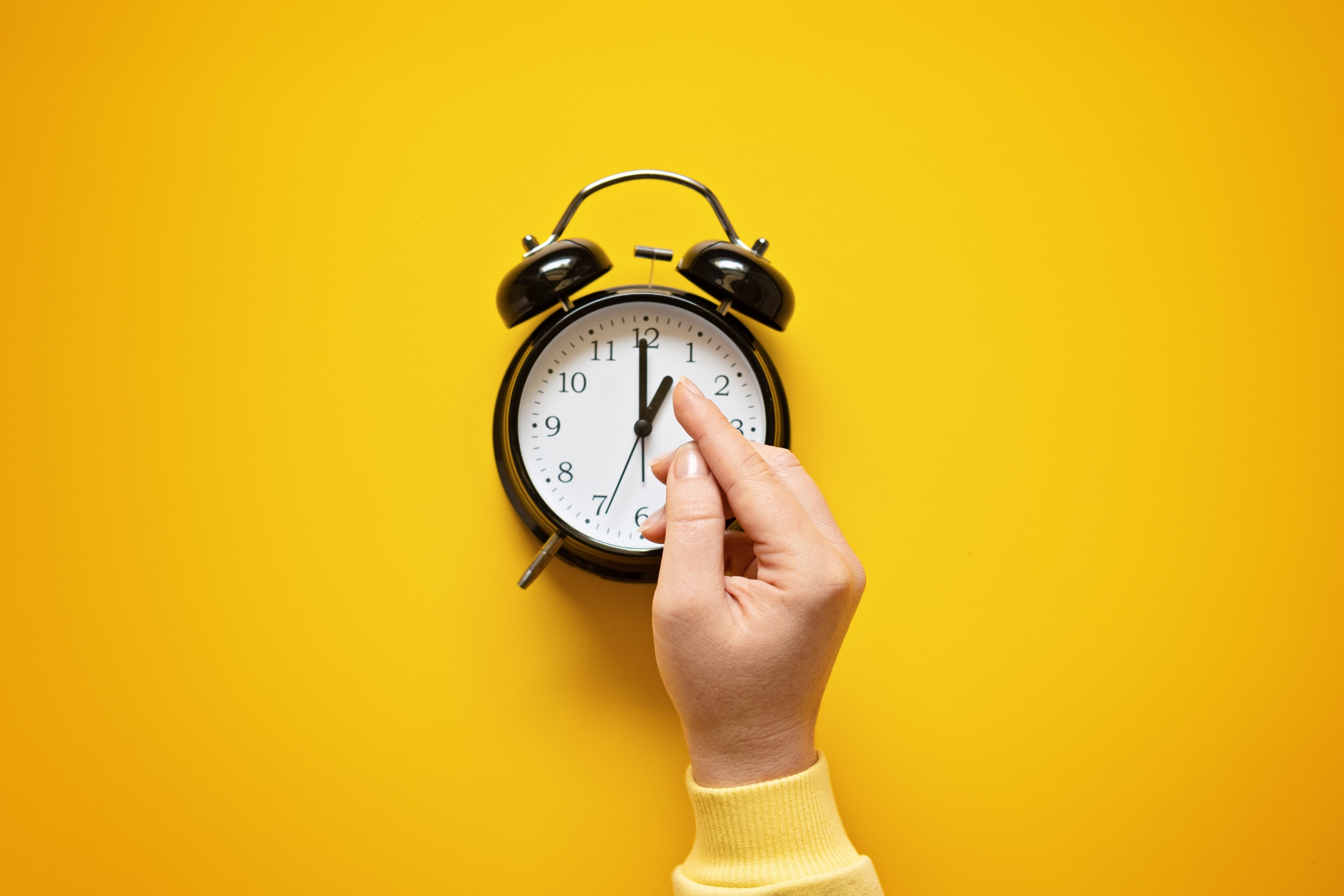 A hand pointing to a clock with a finger pointing to the clock