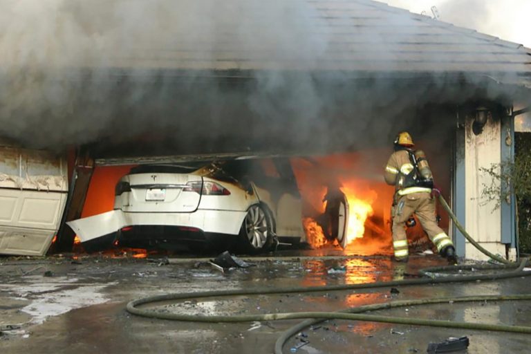 EV on fire on a garage and a firefighter putting it out