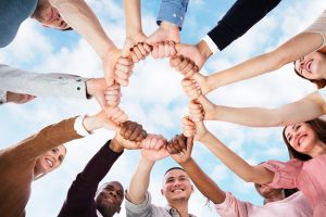 A group of people of all races hold hands in a circle